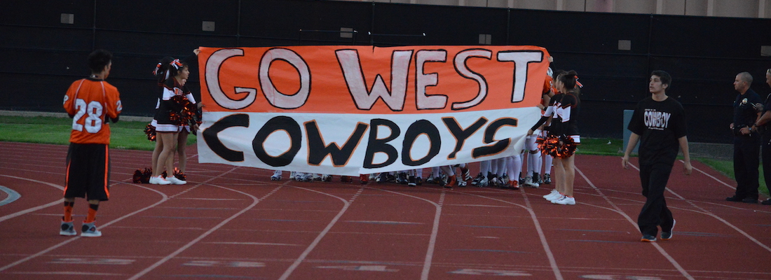 Cheerleaders holding a sign for West Cowboys